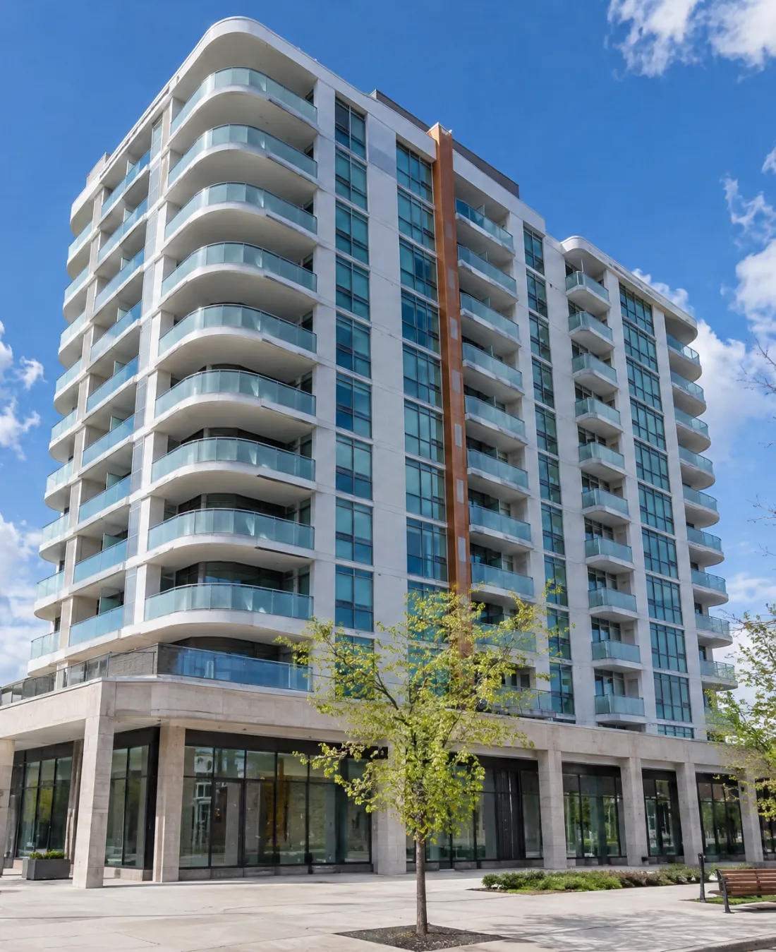 A modern condo tower with curved glass balconies above street-level shops