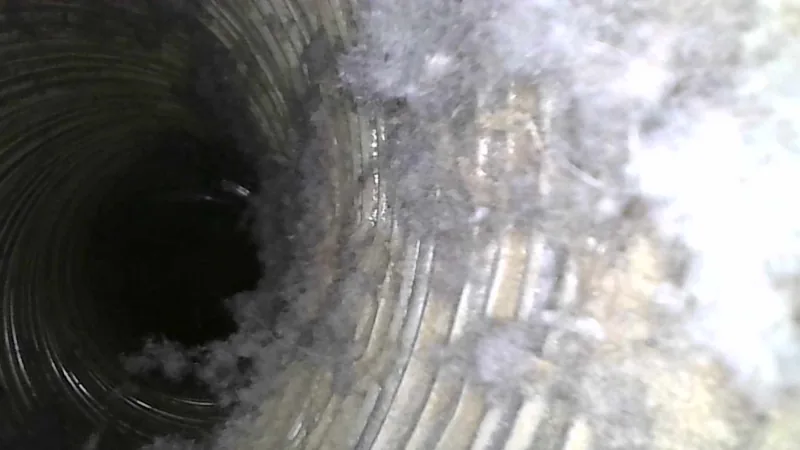 Inside a dryer duct, the ribbed wall caked with matted lint